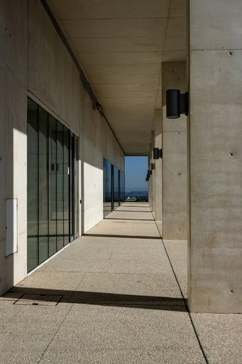 A vertical shot of a long outdoor corridor of a white stone building