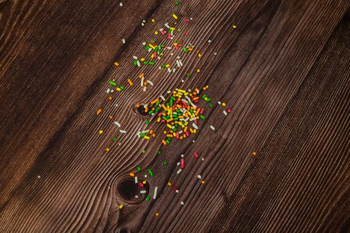 A top view of colorful crumbs of candy spilled on a wooden table