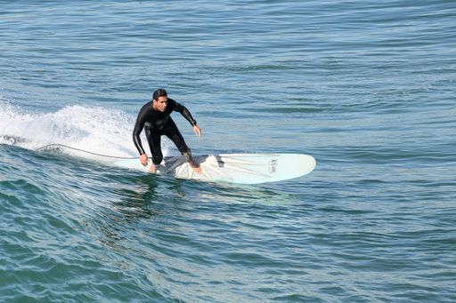 A surfer riding waves at the shore's edge at Huntington Beach, California