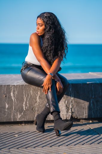 A vertical shot of a young black female posing near the sea