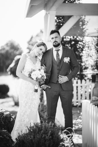 A vertical grayscale shot of a caucasian bride and groom on the wedding day outdoors