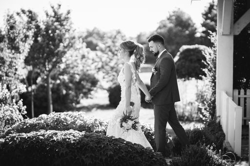 A grayscale shot of a young wedding couple walking in the yard