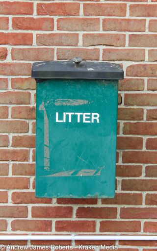 An old litter box leaning against a brick-walled building