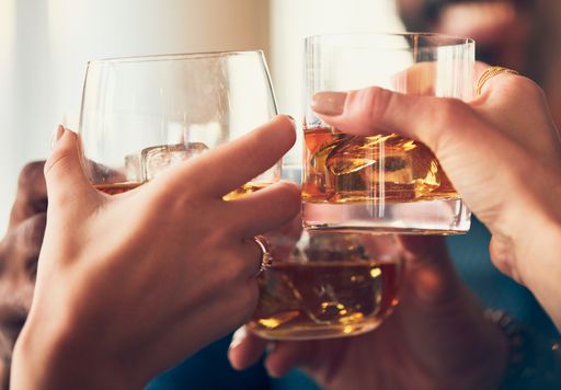 A closeup shot of many people clinking glasses with alcohol at a toast