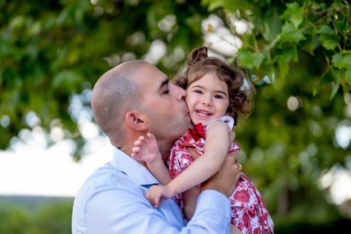 The father hugging and kissing her little daughter while walking in a park