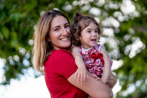 The mother hugging her little daughter while walking in a park