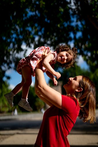 The mother throwing his daughter up while having a nice family time in a park
