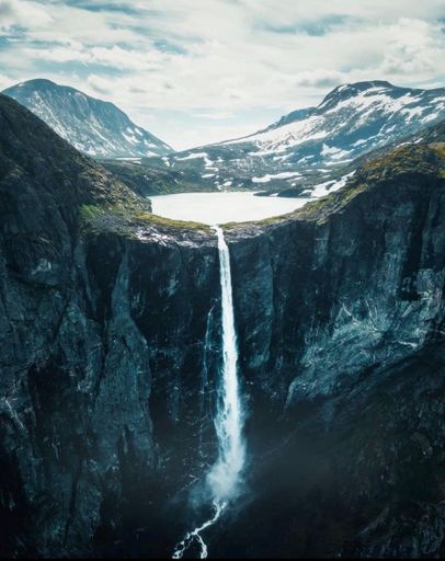 A scenic view of the Mardalsfossen waterfall flowing from a high mountain cliff
