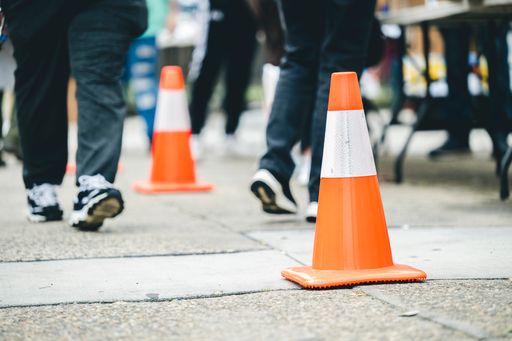 Pedestrians walking beside orange traffic cones on city street