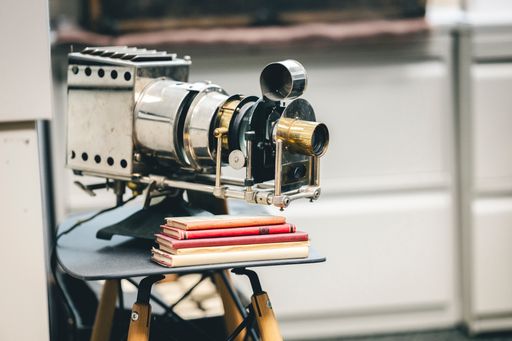 Vintage movie camera, red pencils, and books on a table