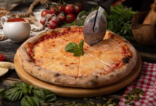A person slicing a cheese pizza into portions