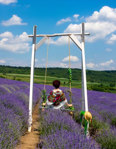 A woman on a wooden swing in a field with lavender flowers