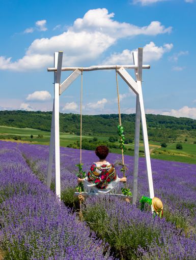 A vertical shot of a woman with a colorful shawl on her shoulders in a lavender field