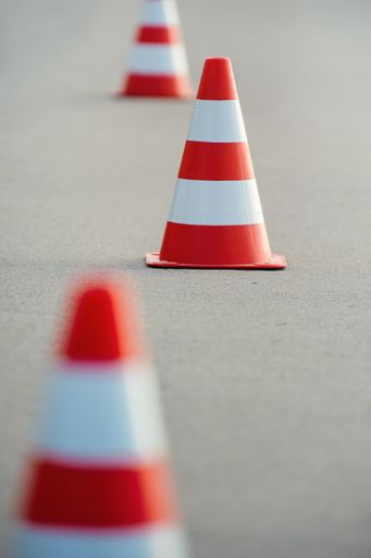 Vertical view of bright orange traffic cones ready for slalom on an asphalt surface.