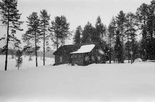 A wide angle shot of a house in front of the trees covered in snow during winter