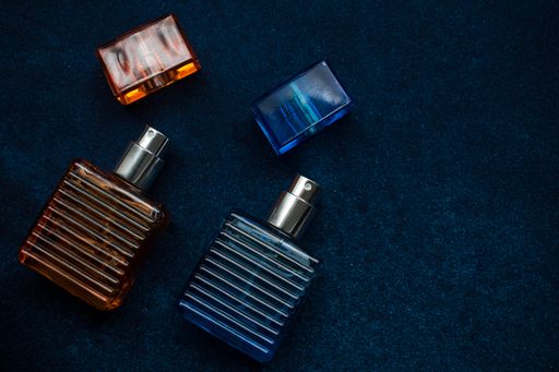 A top view of two perfume bottles on the table with a dark blurry background