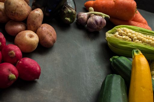 A closeup of fresh raw vegetables on a black wooden table in the kitchen