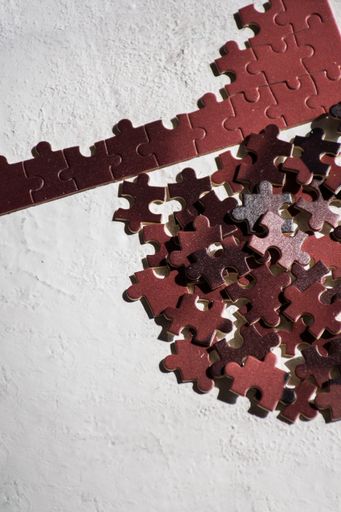 A vertical closeup of puzzle pieces on a concrete background