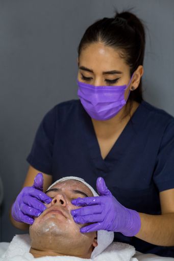 A vertical shot of a doctor wearing a purple mask and gloves treating her patient
