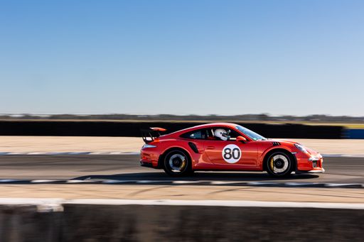 A red Porsche racing on the track in Sebring, United States