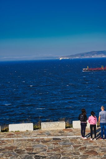 A vertical shot of people standing near the sea in Coruna. Galicia, Spain