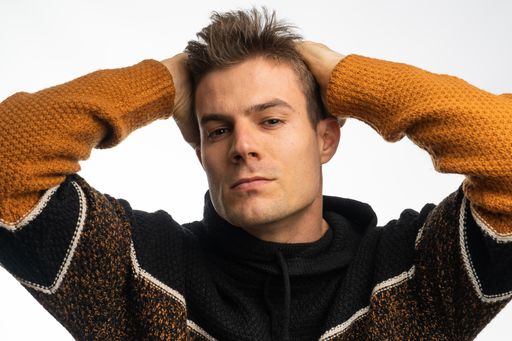 A young Hispanic male holding his head against a white background