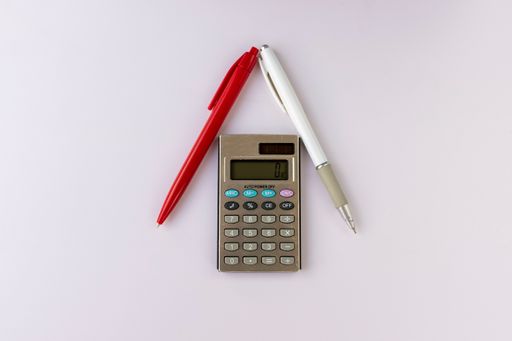 A calculator and pens forming a house isolated on a white background