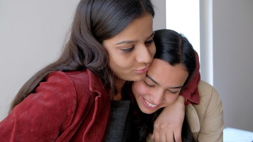 A closeup of two young South Asian women smiling while hugging each other
