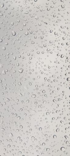 Raindrops on car windshield seen through window in close-up view