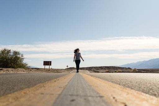 A female walking on the asphalt road under a blue sky in the USA - death valley