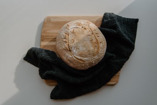 Loaf of bread on wooden cutting board with black cloth