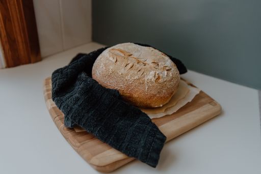 Freshly baked bread on a rustic wooden board with a cloth, displayed on a table