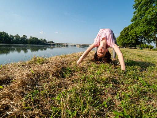 A young Caucasian girl practicing yoga by the river - healthy lifestyle