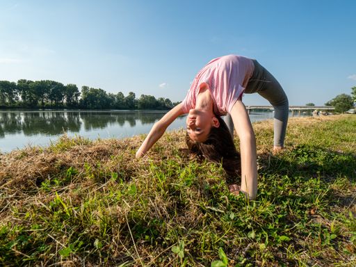 A young Caucasian girl practicing yoga by the river - healthy lifestyle