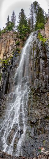 Vertical of a waterfall with rocks, cliff and trees