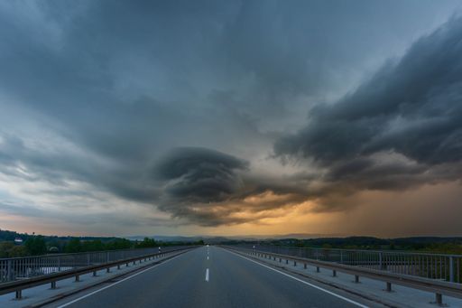 A scenic view of dramatic storm cloud over highway at sunset