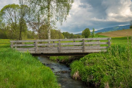 A scenic view of a bridge over a creek in the countryside