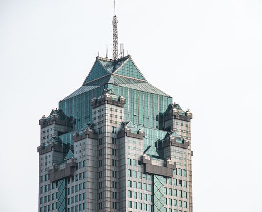 A Skyscraper with blue glass windows and a tower on top of it