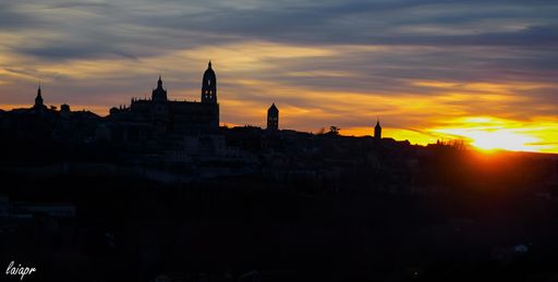 Sun setting over city skyline with hill on side