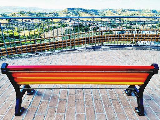 A closeup of a rainbow bench on a terrace surrounded by hills in Spoltore, Italy