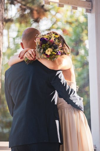 The two individuals embracing each other while holding a bunch of flowers.