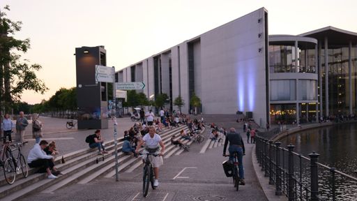 A group of people resting on the steps and riding bicycles on the streets of Berlin, Germany