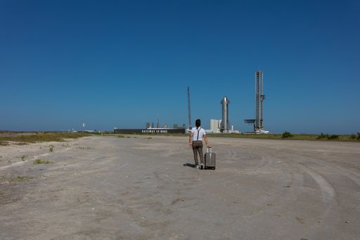 A person walking with a suitcase to the gateaway to Mars at Brownsville, watched from outside