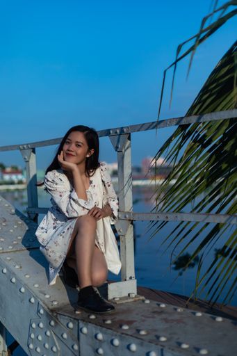 A smiling black-haired Vietnamese girl sitting on a bridge