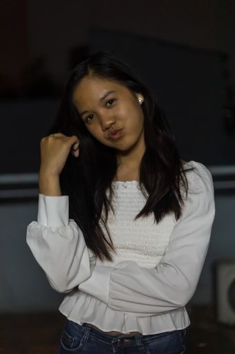 A vertical shot of a Vietnamese girl with pursed lips at night