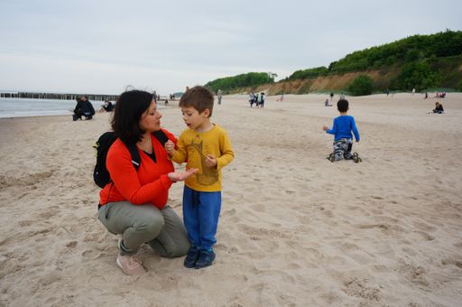 A woman taking to her child from back by the water on the sand at a beach in Trzesacz, Poland