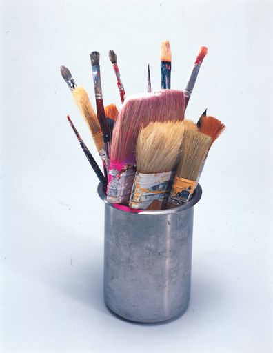 A bunch of used painting tools in a cup on a white background