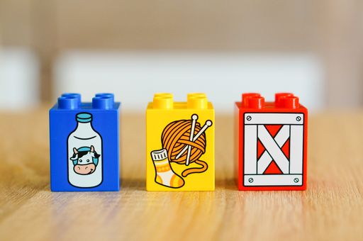 A selective closeup of the colorful plastic Lego Duplo toy blocks with illustrations on a table