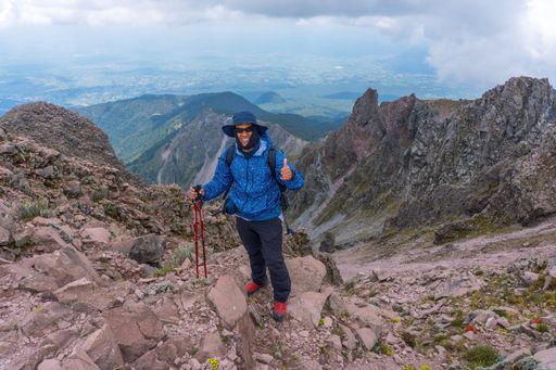 A Hispanic man hiking in the mountains and enjoying the beautiful nature