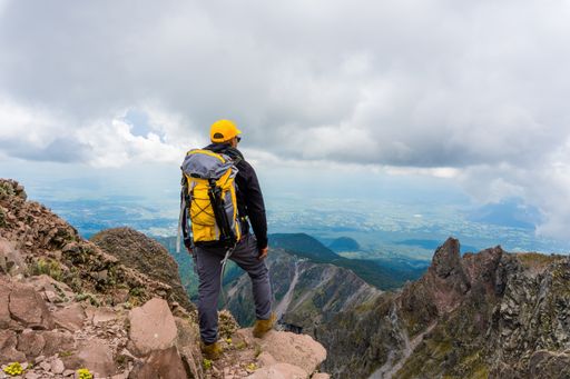 A hiker with a backpack standing on the top of the mountain